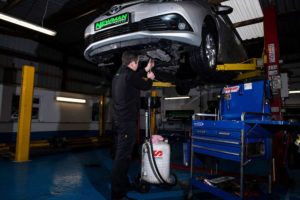 mechanic fixing underbelly of car