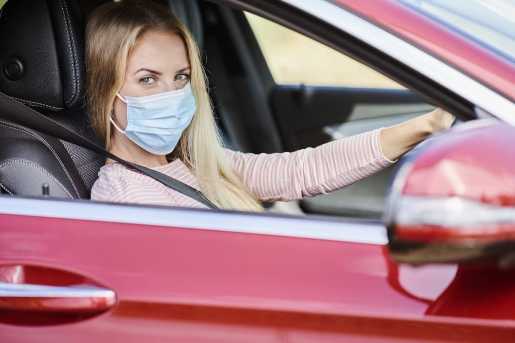 Safe driving, safe living. Woman in car with a facemask